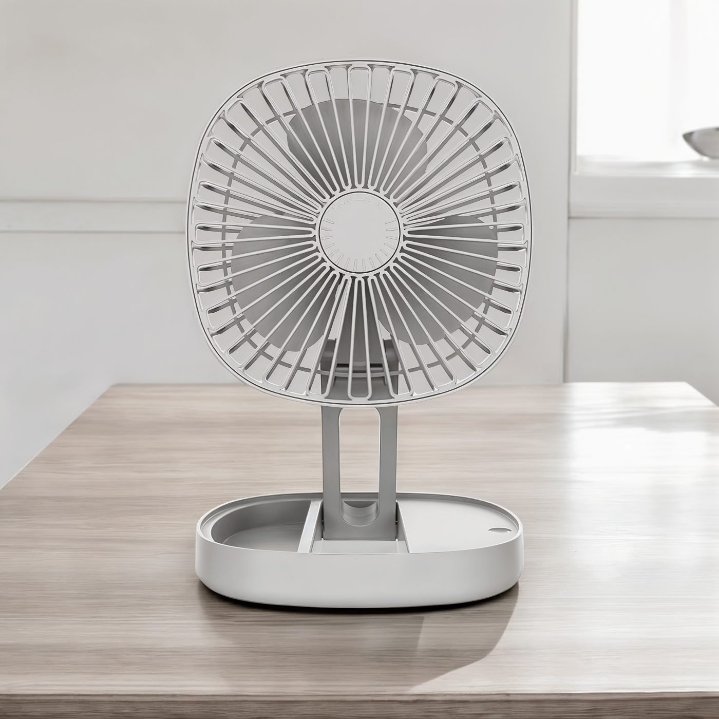 Gray portable folding fan fully extended on a wooden table