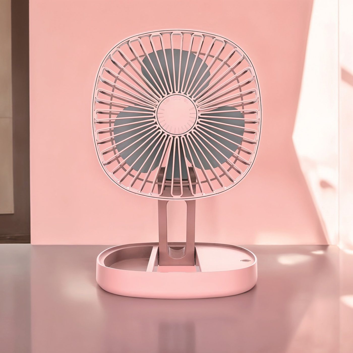 Pink portable folding fan fully extended on a reflective surface