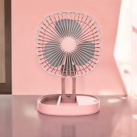 Pink portable folding fan fully extended on a reflective surface