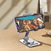 Silver stand holding a smartphone in landscape mode on a desk, playing a video of friends in a car