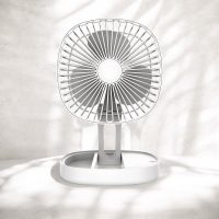White portable folding fan fully extended with sunlight filtering through
