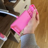 Hand stretching open the pink expanding grip of a gooseneck phone holder, demonstrating the spring mechanism.