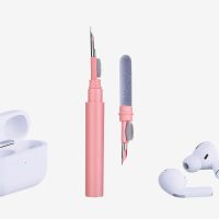 Pink 3-in-1 earphone cleaning tool next to white wireless earphones and open charging case.