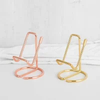 Rose gold and gold serpentine phone stands on white desk