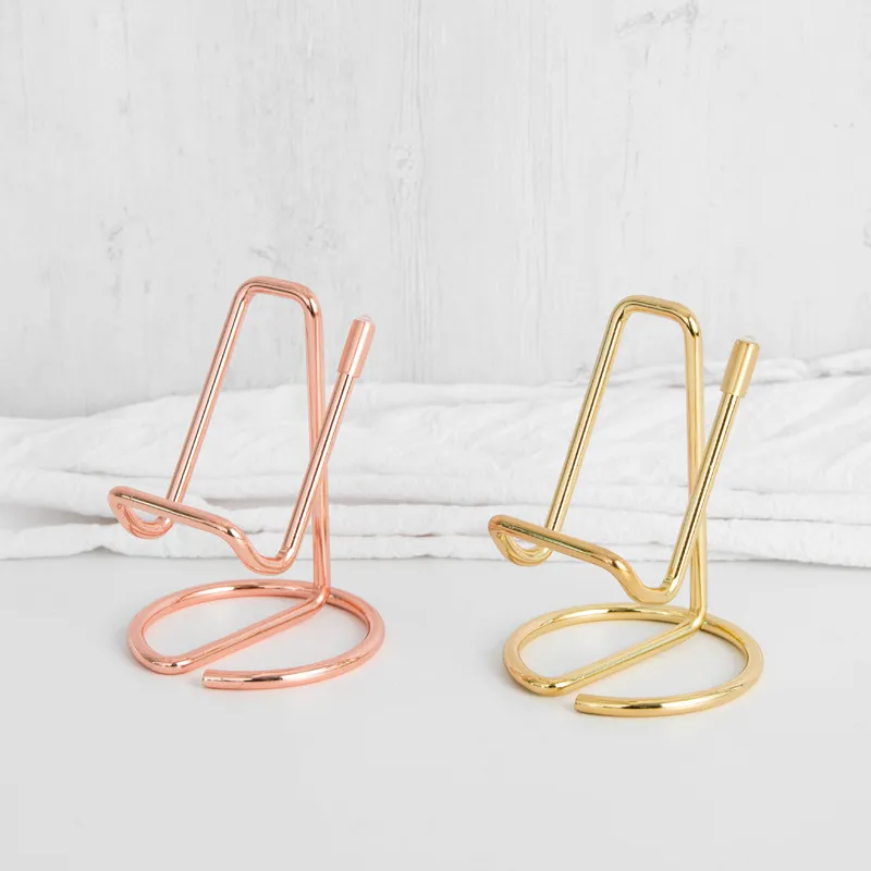 Rose gold and gold serpentine phone stands on white desk